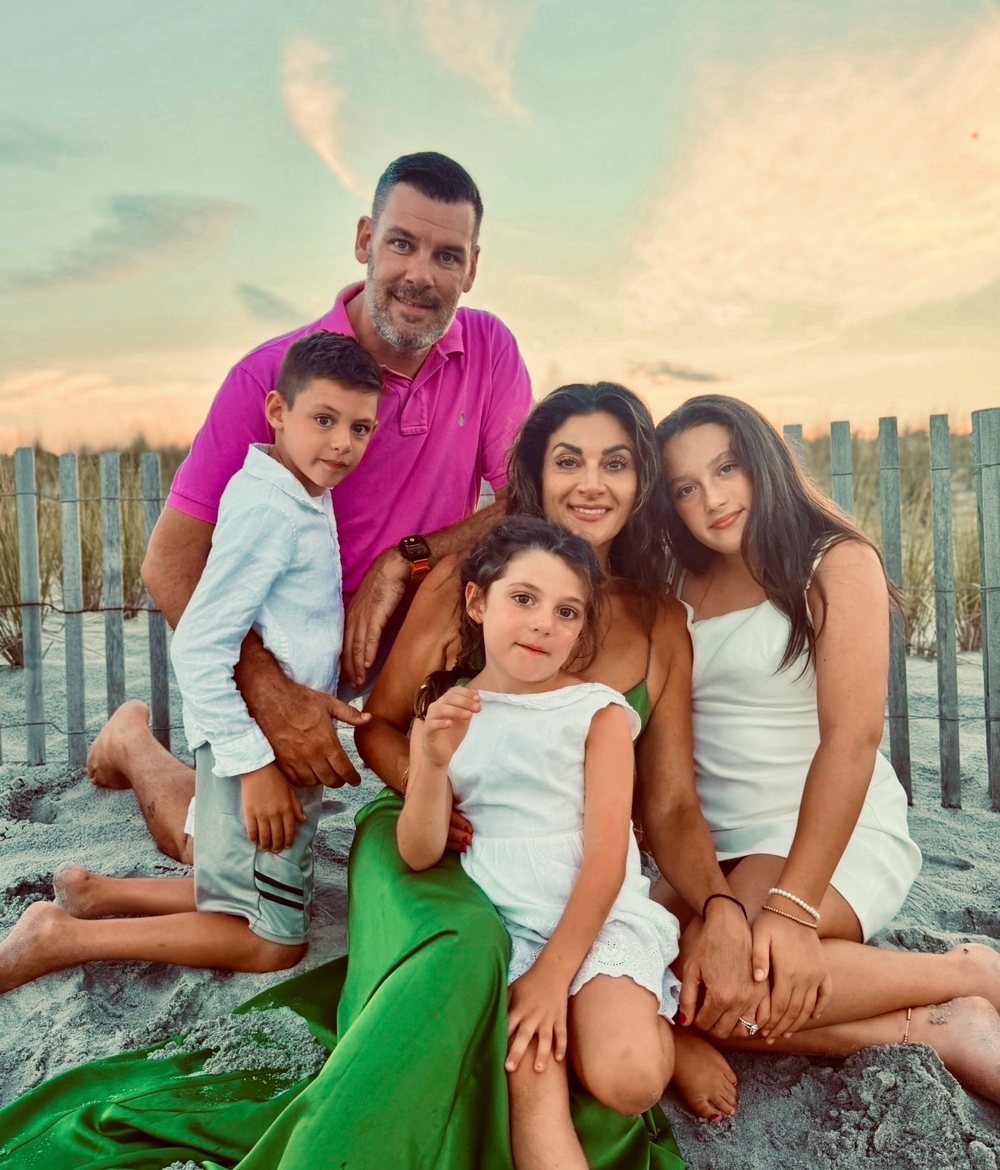 Brian Zusi with his wife and three children on the beach at sunset